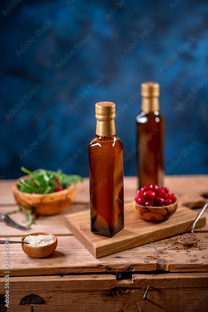 Two bottles of olive oil with bowl of olives and salad on wooden board Two bottles of olive oil with bowl of olives and salad on wooden board