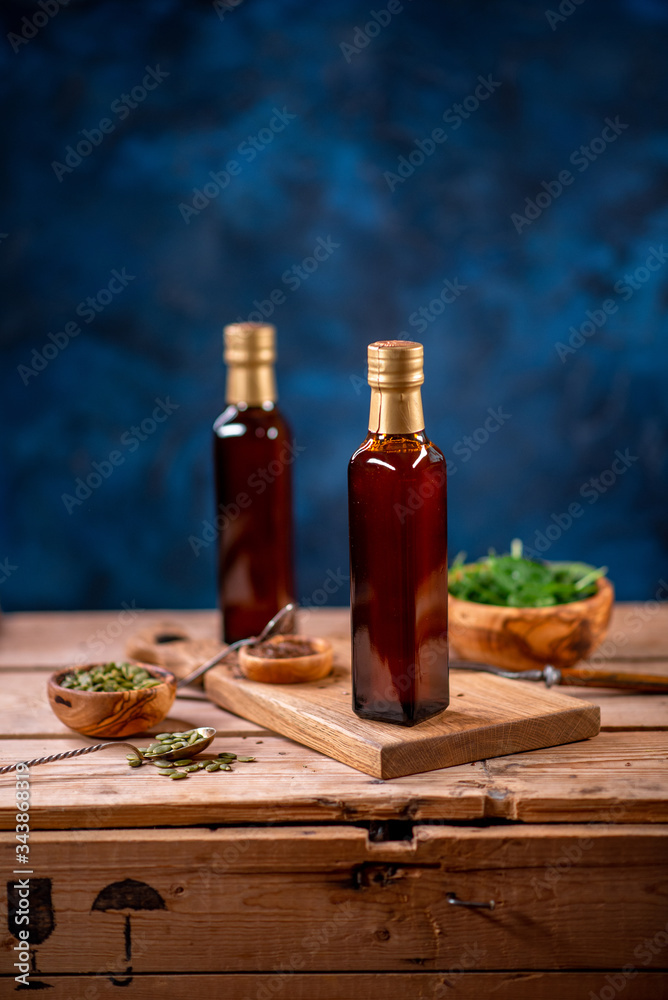 Naklejka Two bottles of olive oil with bowl of olives and salad on wooden board