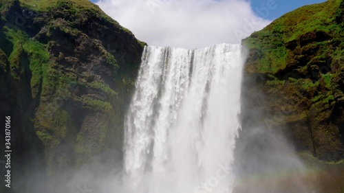 Iceland waterfall Skogafoss in Icelandic nature landscape. Famous tourist attractions and landmarks destination in Icelandic nature landscape on South Iceland. Wide view zoom of a waterfall in Iceland