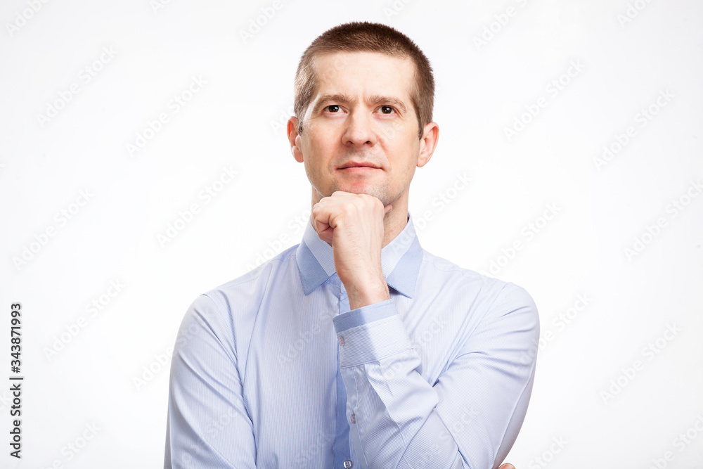 brooding successful man makes a decision, pondering, holding his hand at the chin, in a blue light casual shirt, looking up. Isolated brooding successful man makes a decision, pondering, holding his hand at the chin, in a blue light casual shirt, looking up. Isolated