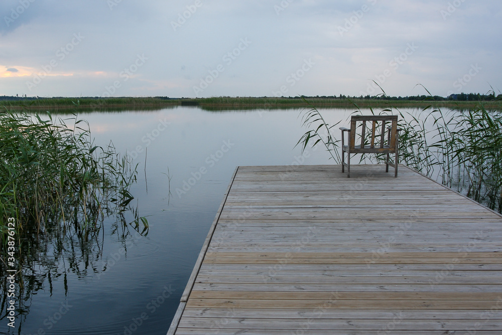 Naklejka premium A chair on a deck on a calm lake