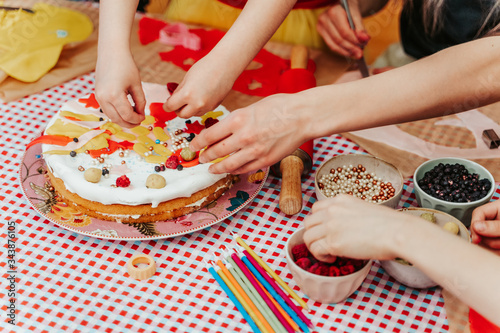 Children preparing homemade birthday cake with colorful topping.