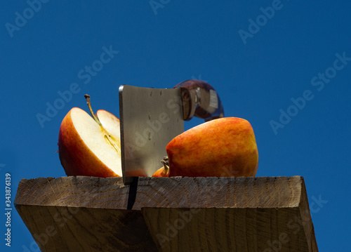 Two halves of apple and knife on wooden board