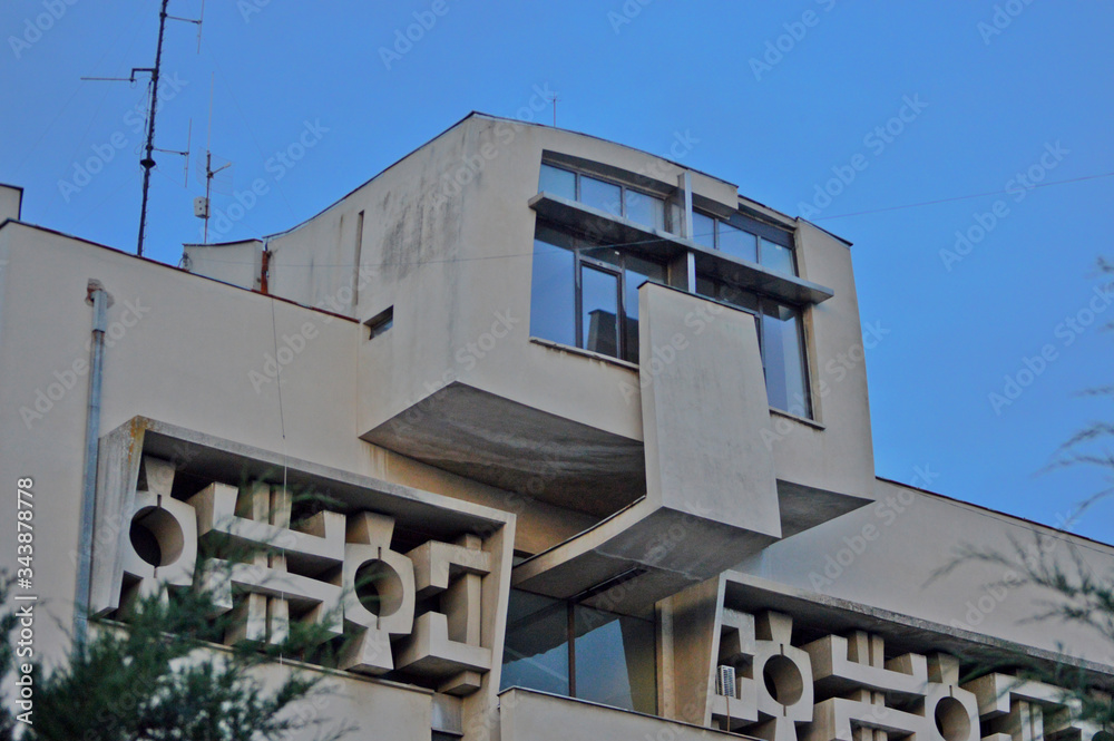 The facade of an old communist building, straight lines and gray concrete