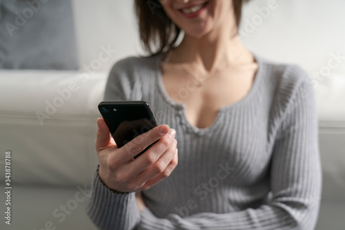 A beautiful Caucasian woman with brown hair at home using her smartphone to shop online