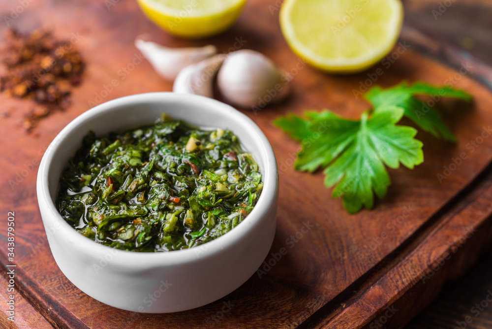 Traditional Argentinian chimichurri sauce against wooden backgroundv Traditional Argentinian chimichurri sauce against wooden backgroundv