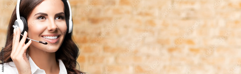 Portrait of cheerful customer support female phone worker, looking up, with copyspace, over loft style wall background. Consulting and assistance service call center. Portrait of cheerful customer support female phone worker, looking up, with copyspace, over loft style wall background. Consulting and assistance service call center.
