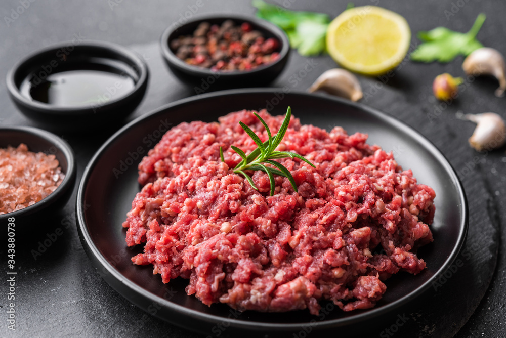 Fresh minced meat ground beef on a black plate against stone background Fresh minced meat ground beef on a black plate against stone background
