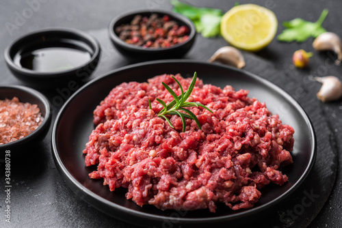 Photos Fresh minced meat ground beef on a black plate against stone background