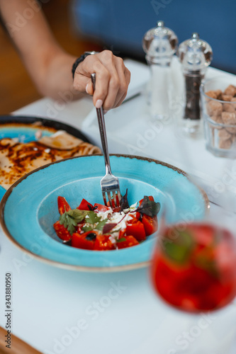 Woman eating salad in a restaurant. Close-up of hands and plates