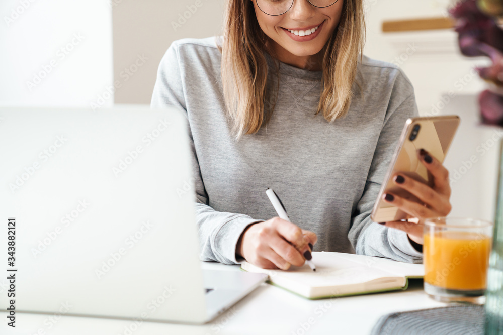 Cropped photo of woman making notes in planner while using cellphone Cropped photo of woman making notes in planner while using cellphone