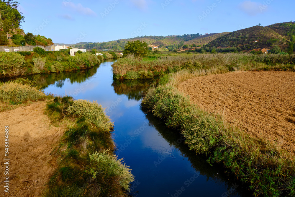 The village of Odeceixe see fron the blue river Ribeira de Seixe. Solo Backpacker Trekking on the Rota Vicentina and Fishermen's Trail in Algarve, Portugal. Walking between cliff, ocean, nature and be