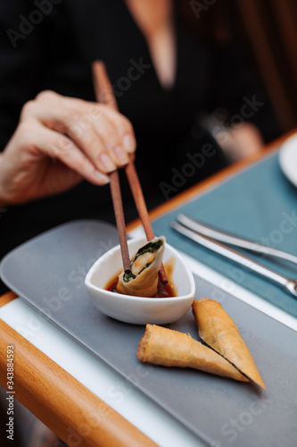 A woman is eating in a chinese restaurant. Close-up of hands and chopsticks