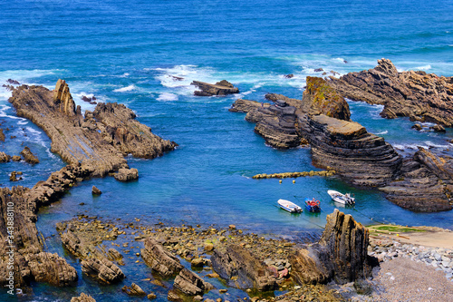 Boats in a natural harbor in the cliff. Solo Backpacker Trekking on the Rota Vicentina and Fishermen's Trail in Alentejo, Portugal. Walking between cliff, ocean, nature and beach.