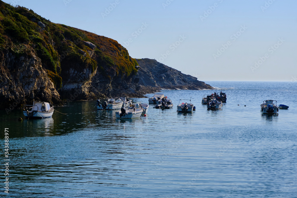 Boats in a natural harbor in the cliff. Solo Backpacker Trekking on the Rota Vicentina and Fishermen's Trail in Alentejo, Portugal. Walking between cliff, ocean, nature and beach.