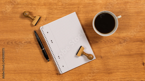 Holzschreibtisch mit Notizbuch  Kugelschreiber  Holzstempel und Kaffeetasse 