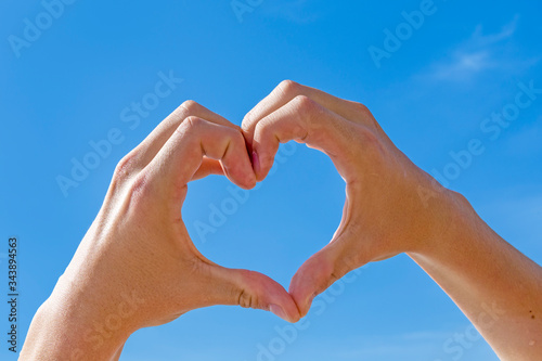 heart shape with hand under blue sky