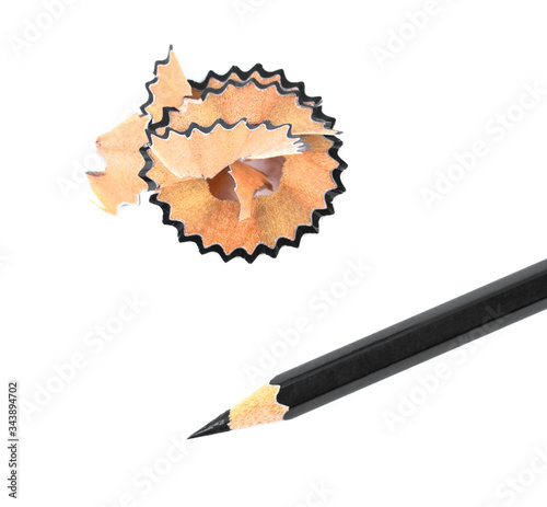 Some pencil shavings placed beside a black color wood pencil crayon on a white background