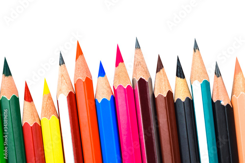 Different colored wooden pencil crayons placed in a row in front of a white background