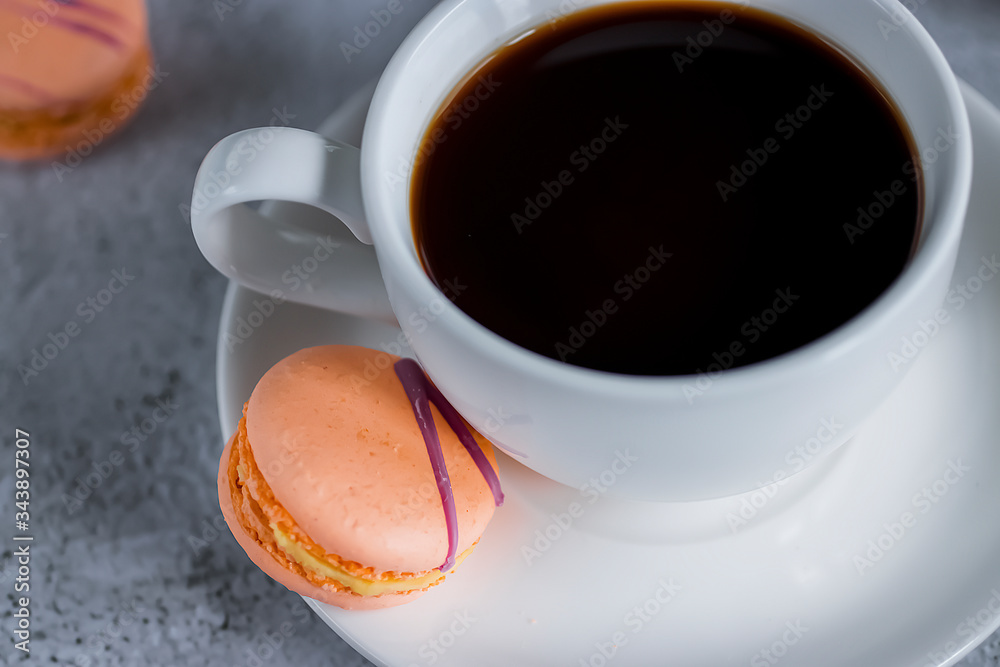 White cup espresso and bright macaroon cakes on concrete background. Close-up. White cup espresso and bright macaroon cakes on concrete background. Close-up.