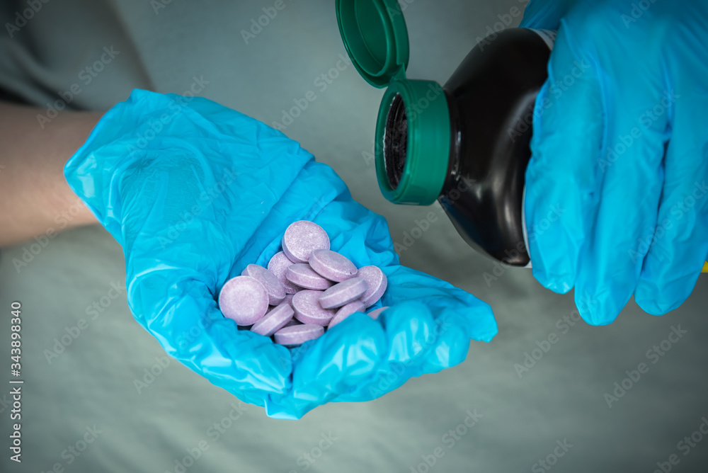 Fototapeta premium Hands wearing surgical gloves and holding medication bottle and vitamin C tablets