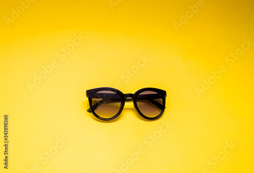 Black glasses on a yellow background with an open seat. Black semi-transparent glasses.