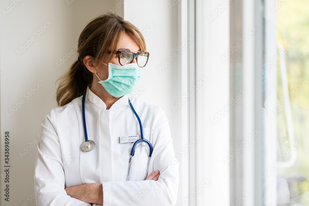 Stressed female doctor portrait while wearing face mask in the hospital Stressed female doctor portrait while wearing face mask in the hospital
