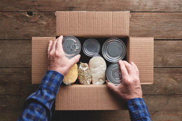 a person packing a donation box with food items