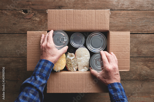a person packing a donation box with food items photo