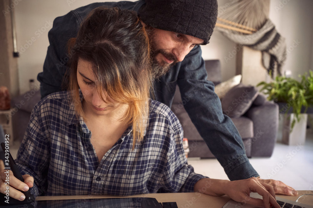 Young couple in the living room, girl working remotely because of the global pandemic. Young couple in the living room, girl working remotely because of the global pandemic.