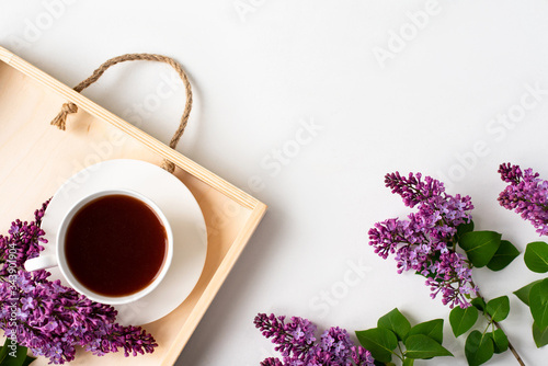 Branches and flowers of lilac, violet color, on a white background. Cup with coffee, cocoa, spring breakfast. Creative flat lay, frame for text. Minimalistic design. Panoramic banner background with 