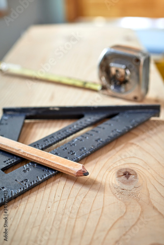 various tools at a construction site including a framing square, tape measure and pencil. © goodmanphoto