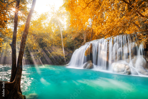 Waterfall and blue emerald water in autumn forest with sun flare and sunlight in morning. Erawan Waterfall step 2nd. Beautiful nature rock waterfall steps in rainforest at Kanchanaburi, Thailand © cattyphoto