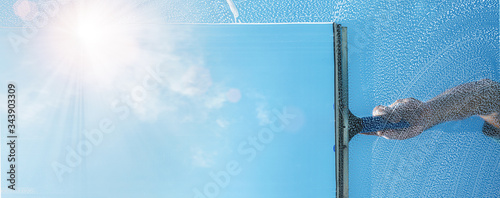 Fotografía window cleaner cleaning window with squeegee and wiper on a sunny day