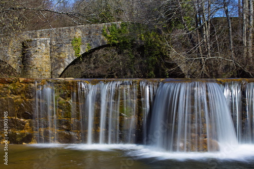 Sarria, Araba/Basque Country; Mar. 18, 2017. Dam and an old bridge over the Bayas river as it passes through Sarria in the Natural Park of Gorbeia.