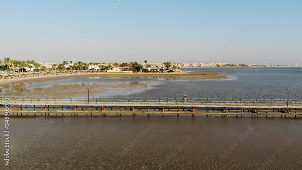 Beautiful girl walks on the pier and enjoys the sea. Drone flight Beautiful girl walks on the pier and enjoys the sea. Drone flight