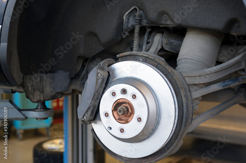 Car repair in a car service. Replacing brakes in a car service. New brake disc close up.