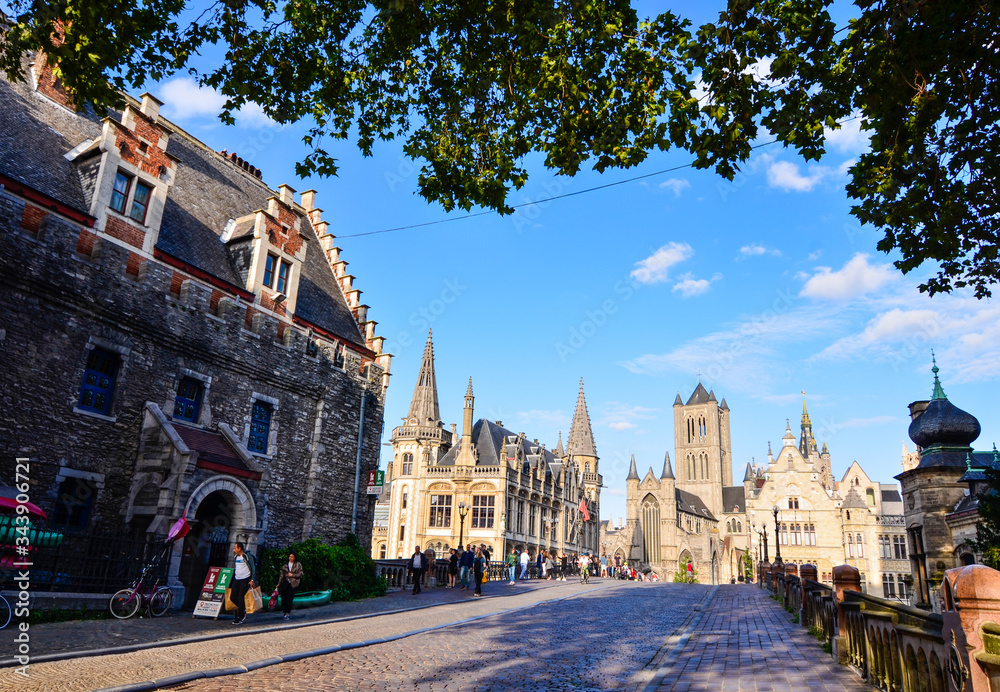 Fototapeta premium Ghent, Belgium, August 2019. In the historic center, one of the most beautiful views of the city: the bridge of St Michael. in the direction of the church of San Nicola. People stop to enjoy the view.