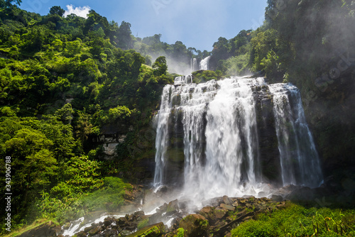 Flowing water of large and high waterfall on mountain cliff in the tropical rain forest. Beautiful nature waterfall in Bolaven Plateau  southern Laos  Tad kamud waterfall