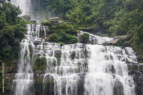 Flowing water of large and high waterfall on mountain cliff in the tropical rain forest. Beautiful nature waterfall in Bolaven Plateau, southern Laos, Tad kamud waterfall
