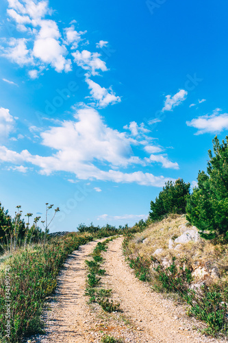 Mountain path. Hiking trail with beautiful bright sky. Active lifestyle concept. Road trip with seascape view over Adriatic coast. Active vacation concept. Background with copy space.Adventure time.