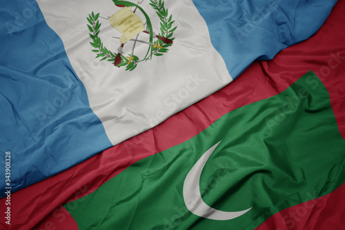 waving colorful flag of maldives and national flag of guatemala. photo