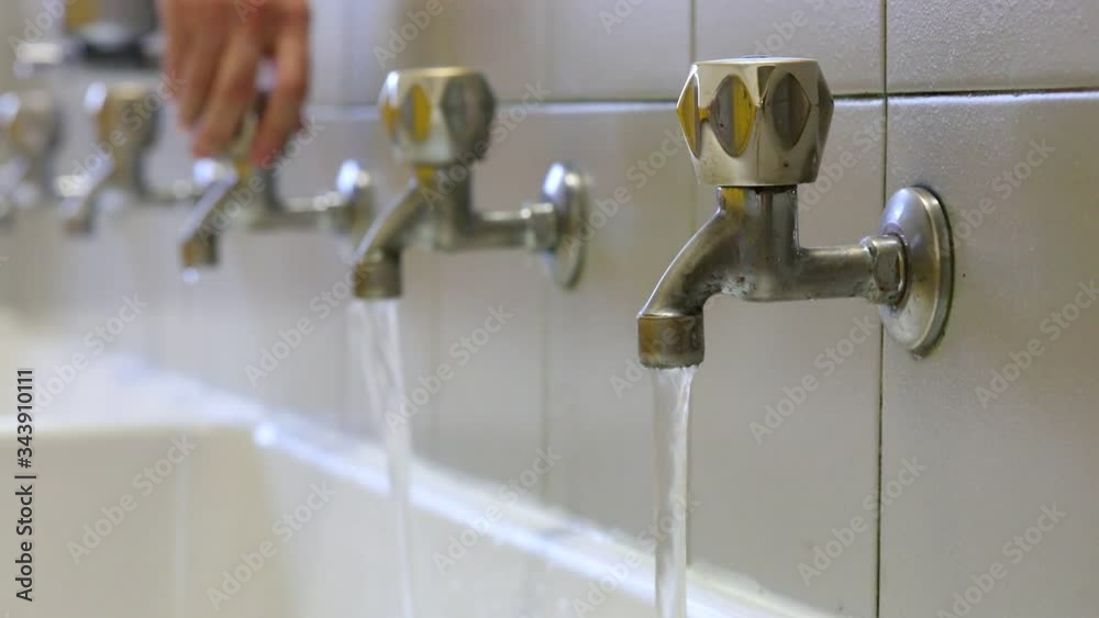 hand of the young man who closes the water taps to avoid waste hand of the young man who closes the water taps to avoid waste
