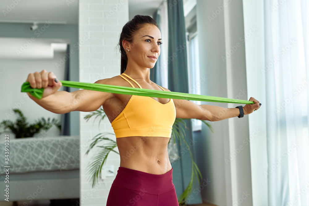 Φωτογραφία Young muscular build woman exercising with resistance band at home