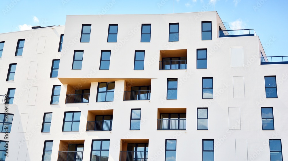 Contemporary residential building exterior in the daylight. Modern apartment buildings on a sunny day with a blue sky. Facade of a modern apartment building