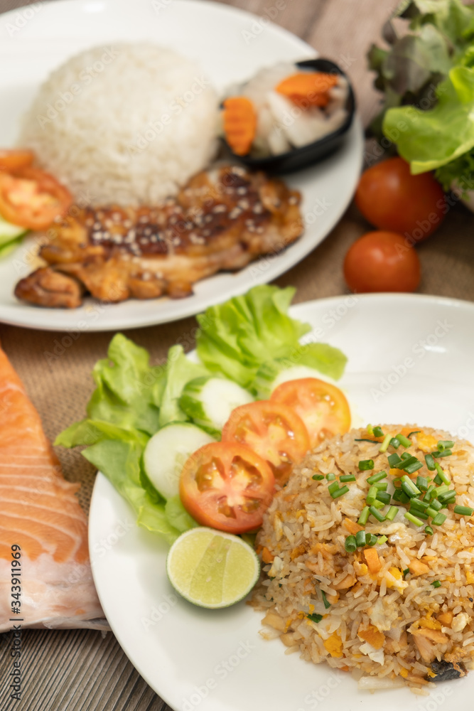 Fried rice with egg and grilled salmon, foreground with chicken teriyaki rice on the wooden table -Stock photo