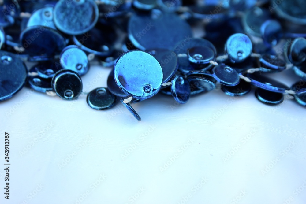 Blue shiny decoration on a white background. Christmas blue beads isolated on white with place for text. Close-up new year background with Christmas balls toned trendy classic blue color. holiday