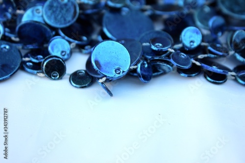 Blue shiny decoration on a white background. Christmas blue beads isolated on white with place for text. Close-up new year background with Christmas balls toned trendy classic blue color. holiday