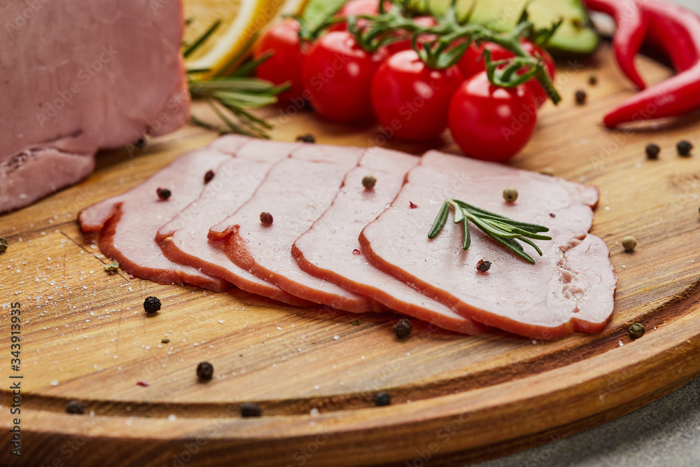 Sliced ham with spices, lettuce, avocado and tomatoes on wooden cutting board. Сold meat plate. Fresh prosciutto Sliced ham with spices, lettuce, avocado and tomatoes on wooden cutting board. Сold meat plate. Fresh prosciutto