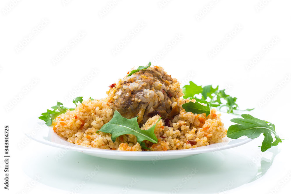 boiled bulgur groats with vegetables and meatballs in a plate